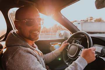 Image showing A man with a sunglasses driving a car at sunset. The concept of car travel