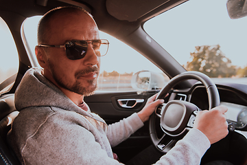 Image showing A man with a sunglasses driving a car at sunset. The concept of car travel