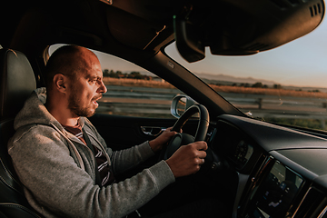 Image showing A man with a sunglasses driving a car at sunset. The concept of car travel