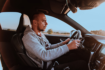 Image showing A man with a sunglasses driving a car at sunset. The concept of car travel