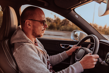 Image showing A man with a sunglasses driving a car at sunset. The concept of car travel