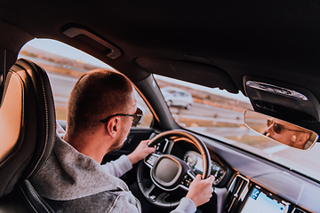 Image showing A man with a sunglasses driving a car at sunset. The concept of car travel