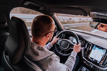 Image showing A man with a sunglasses driving a car at sunset. The concept of car travel