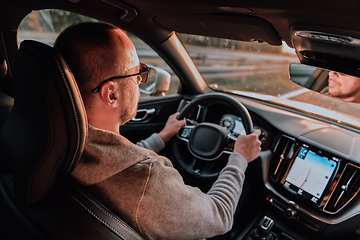 Image showing A man with a sunglasses driving a car at sunset. The concept of car travel