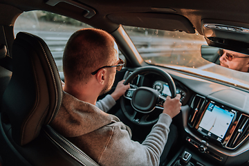 Image showing A man with a sunglasses driving a car at sunset. The concept of car travel