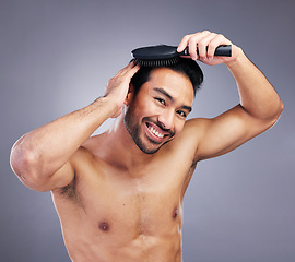 Image showing Portrait, beauty or happy man brushing hair in grooming with salon haircare product on studio background. Smile, brush or confident healthy Asian male model with cool hairstyle in morning routine