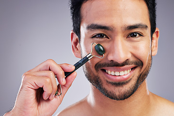 Image showing Happy man, portrait or face massage with roller or product for healthy skincare on studio background. Cheek, crystal stone treatment or male model with facial dermatology cosmetic for beauty glow