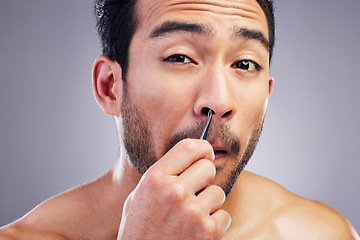 Image showing Tweezer, nose hair and portrait of man in studio for beauty, hygiene or grooming. Pain, epilation and face of an asian male person for skincare, self care and cosmetic tools on grey background