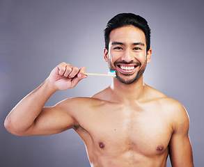 Image showing Dental, portrait and a man brushing teeth on a studio background for cleaning, grooming and hygiene. Happy, wellness and an Asian person with a toothbrush for care of mouth isolated on a backdrop