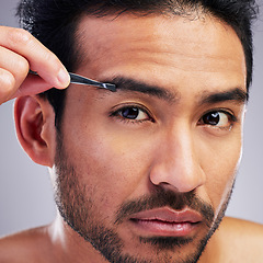 Image showing Eyebrow, tweezer and portrait of a man in studio for beauty, hygiene or grooming. Hair removal, epilation and face of serious asian person for skincare, self care or cosmetic tools on grey background