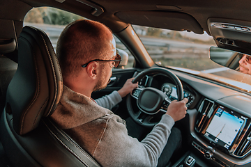 Image showing A man with a sunglasses driving a car at sunset. The concept of car travel