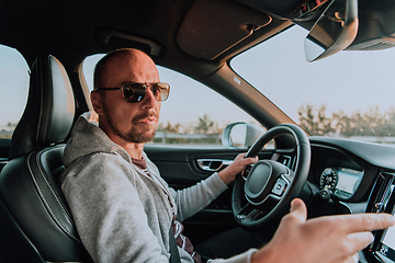 Image showing A man with a sunglasses driving a car at sunset. The concept of car travel