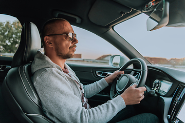 Image showing A man with a sunglasses driving a car at sunset. The concept of car travel