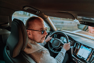 Image showing A man with a sunglasses driving a car at sunset. The concept of car travel