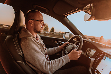 Image showing A man with a sunglasses driving a car at sunset. The concept of car travel