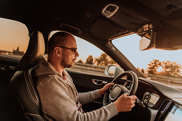 Image showing A man with a sunglasses driving a car at sunset. The concept of car travel