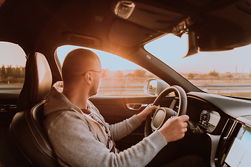 Image showing A man with a sunglasses driving a car at sunset. The concept of car travel