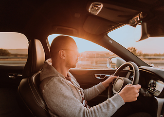 Image showing A man with a sunglasses driving a car at sunset. The concept of car travel