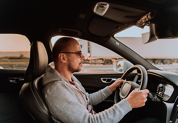 Image showing A man with a sunglasses driving a car at sunset. The concept of car travel