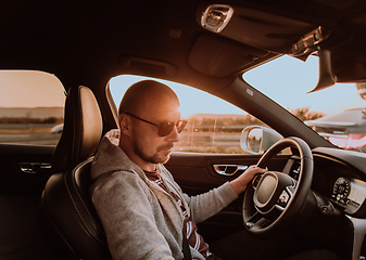 Image showing A man with a sunglasses driving a car at sunset. The concept of car travel