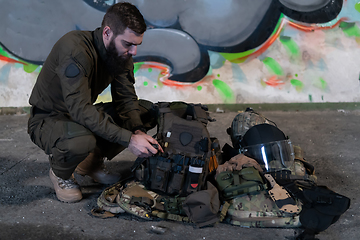 Image showing Army body armor, helmet and ammunition, Kalashnikov assault rifle with matrons and first aid tourniquet composition on brown wood. Army body armor. flat laying. military concept.