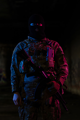 Image showing Army soldier in Combat Uniforms with an assault rifle and combat helmet night mission dark background. Blue and purple gel light effect.