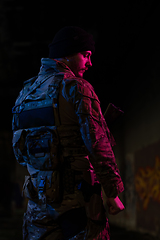 Image showing Army soldier in Combat Uniforms with an assault rifle and combat helmet night mission dark background. Blue and purple gel light effect.