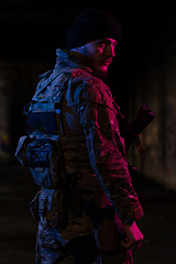 Image showing Army soldier in Combat Uniforms with an assault rifle and combat helmet night mission dark background. Blue and purple gel light effect.