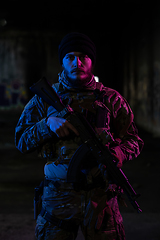 Image showing Army soldier in Combat Uniforms with an assault rifle and combat helmet night mission dark background. Blue and purple gel light effect.