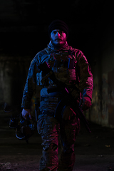 Image showing Army soldier in Combat Uniforms with an assault rifle and combat helmet night mission dark background. Blue and purple gel light effect.