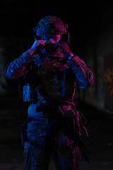 Image showing Army soldier in Combat Uniforms with an assault rifle and combat helmet night mission dark background. Blue and purple gel light effect.