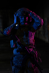 Image showing Army soldier in Combat Uniforms with an assault rifle and combat helmet night mission dark background. Blue and purple gel light effect.