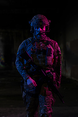 Image showing Army soldier in Combat Uniforms with an assault rifle and combat helmet night mission dark background. Blue and purple gel light effect.