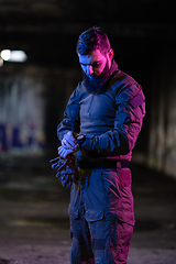 Image showing Modern warfare soldier checking navigation, time and other information on a smartwatch. Dark night black background.