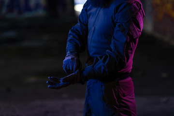 Image showing Modern warfare soldier checking navigation, time and other information on a smartwatch. Dark night black background.