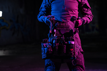 Image showing Army soldier in Combat Uniforms with an assault rifle and combat helmet night mission dark background. Blue and purple gel light effect.