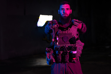 Image showing Army soldier in Combat Uniforms with an assault rifle and combat helmet night mission dark background. Blue and purple gel light effect.