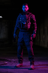 Image showing Army soldier in Combat Uniforms with an assault rifle and combat helmet night mission dark background. Blue and purple gel light effect.