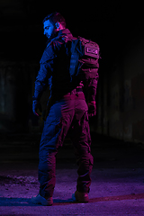 Image showing Army soldier in Combat Uniforms with an assault rifle and combat helmet night mission dark background. Blue and purple gel light effect.