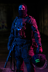 Image showing Army soldier in Combat Uniforms with an assault rifle and combat helmet night mission dark background. Blue and purple gel light effect.