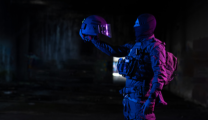 Image showing Army soldier in Combat Uniforms with an assault rifle and combat helmet night mission dark background. Blue and purple gel light effect.