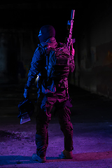 Image showing Army soldier in Combat Uniforms with an assault rifle and combat helmet night mission dark background. Blue and purple gel light effect.