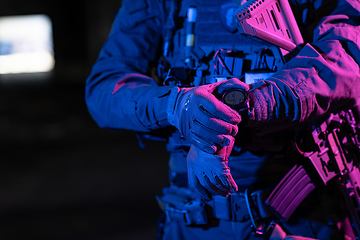 Image showing Modern warfare soldier checking navigation, time and other information on a smartwatch. Dark night black background.