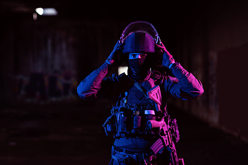 Image showing Army soldier in Combat Uniforms with an assault rifle and combat helmet night mission dark background. Blue and purple gel light effect.