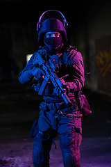 Image showing Army soldier in Combat Uniforms with an assault rifle and combat helmet night mission dark background. Blue and purple gel light effect.