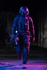 Image showing Army soldier in Combat Uniforms with an assault rifle and combat helmet night mission dark background. Blue and purple gel light effect.