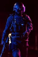 Image showing Army soldier in Combat Uniforms with an assault rifle and combat helmet night mission dark background. Blue and purple gel light effect.