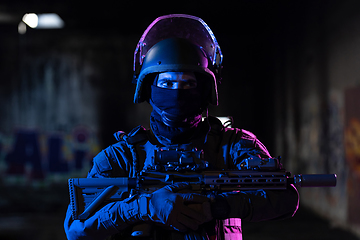 Image showing Army soldier in Combat Uniforms with an assault rifle and combat helmet night mission dark background. Blue and purple gel light effect.