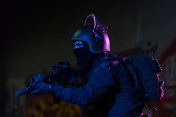 Image showing Army soldier in Combat Uniforms with an assault rifle and combat helmet night mission dark background. Blue and purple gel light effect.