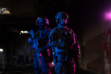 Image showing Modern warfare soldiers in dark with combat ammunition and weapons in the hands of equipped laser sights are in battle order. Mixed media.